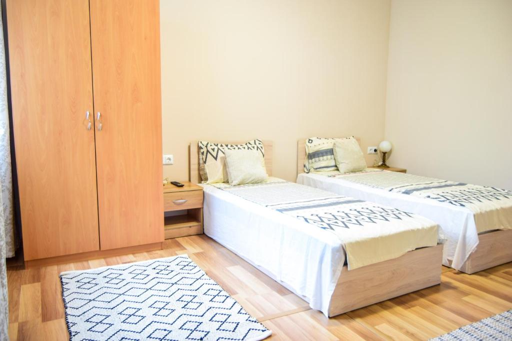 a bedroom with two beds and a cabinet at Стаи за гости Люляк 21 in Pavel Banya