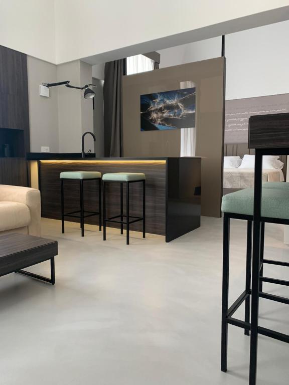 uma sala de estar com três bancos de bar e uma cama em DONNA CATERINA LUXURY STAYandSPA em Monopoli