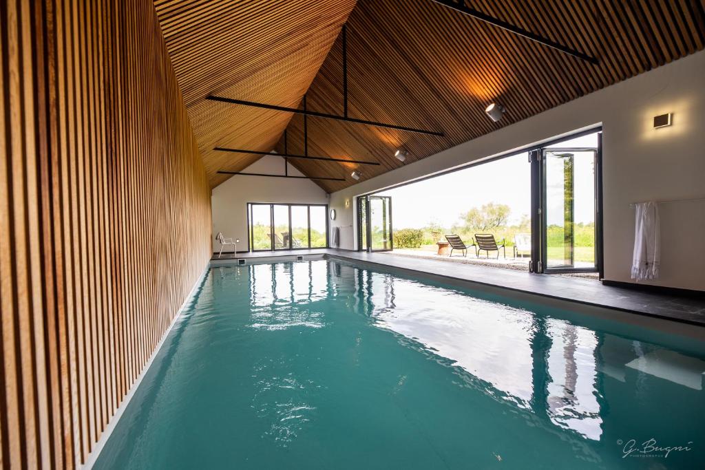 an indoor swimming pool with blue water in a house at côté verger B&B in Battice