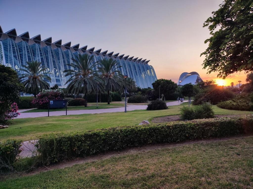 un parco di fronte a un grande edificio con palme di City of Arts & Sciences Rooms & Suites at Bruno Valencia Apartments - Oceanografic - Ciudad de las Artes y las Ciencias a Valencia