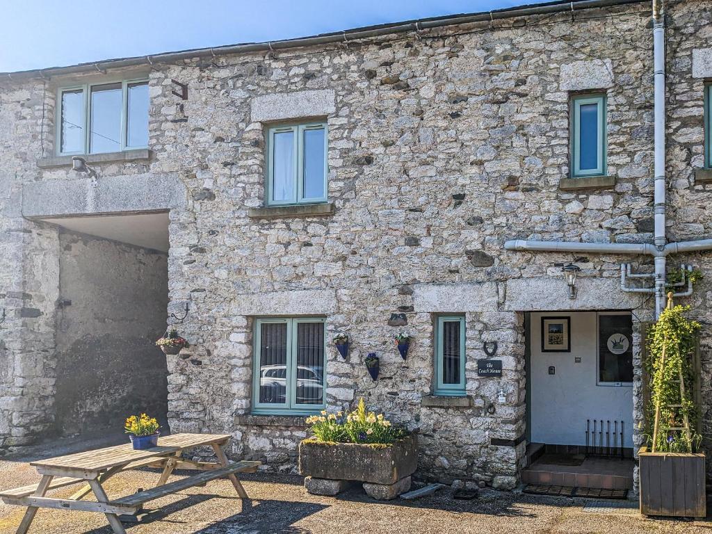 a stone building with a picnic table in front of it at The Coach House - Uk38044 in Beetham