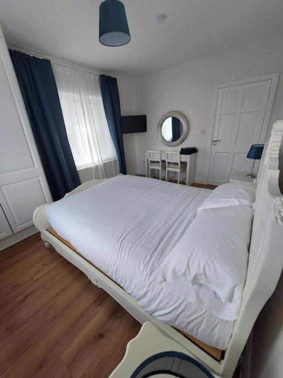 a white bed in a room with a window at Grá na Farraige in Enniscrone