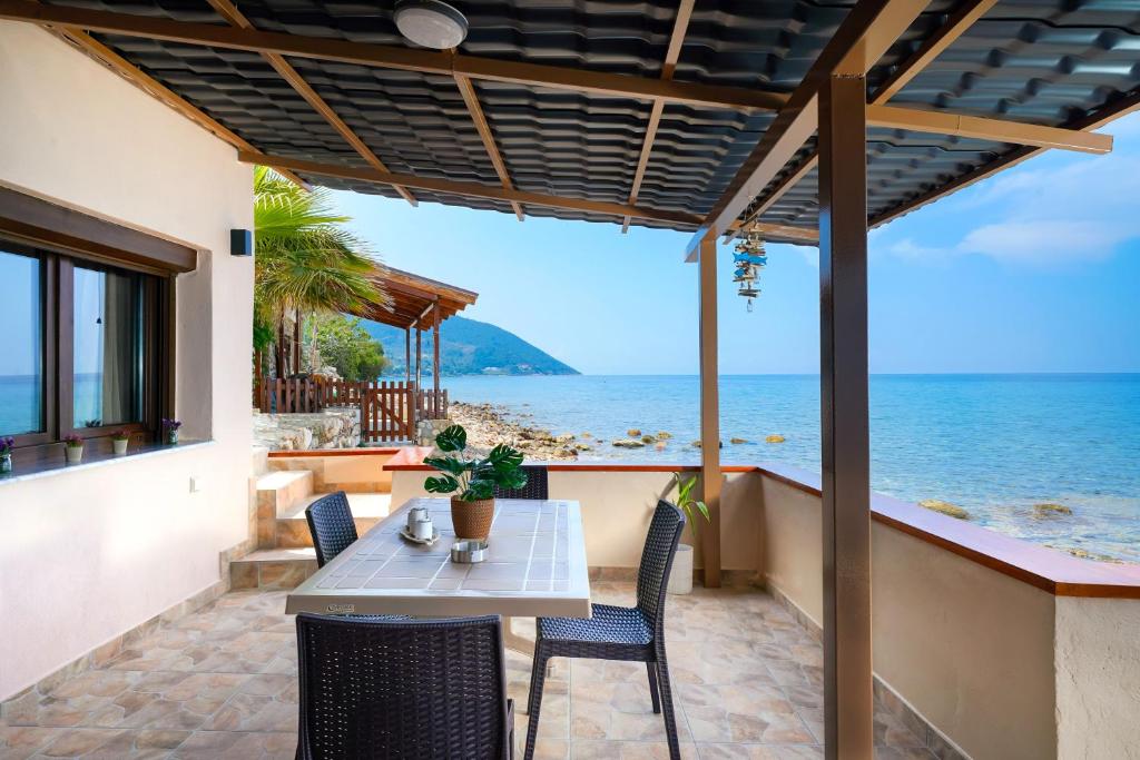 una mesa y sillas en un patio con vistas al océano en To Kyma - Seafront House, en Skala Kallirakhis