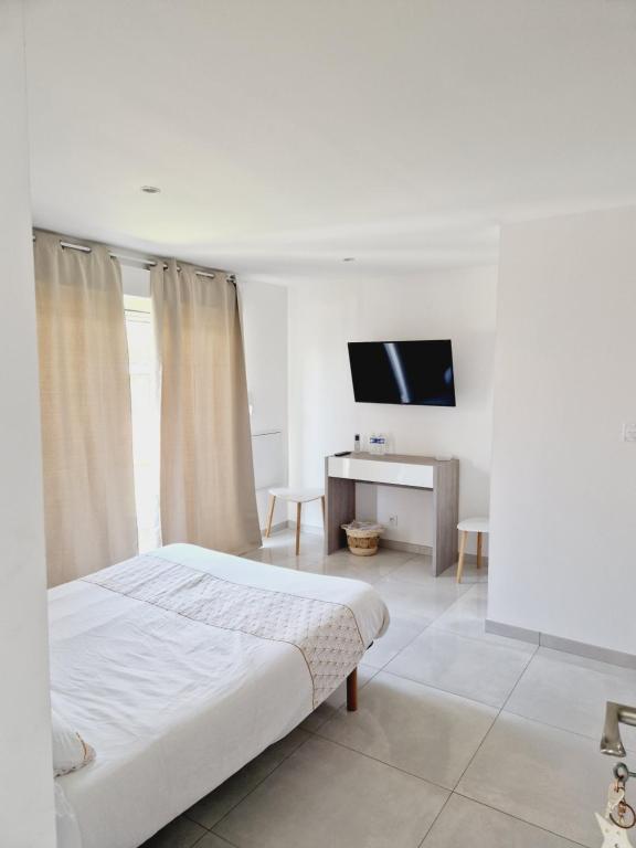 - une chambre blanche avec un lit et une télévision dans l'établissement Chez Manon et Jimmy, à Agde