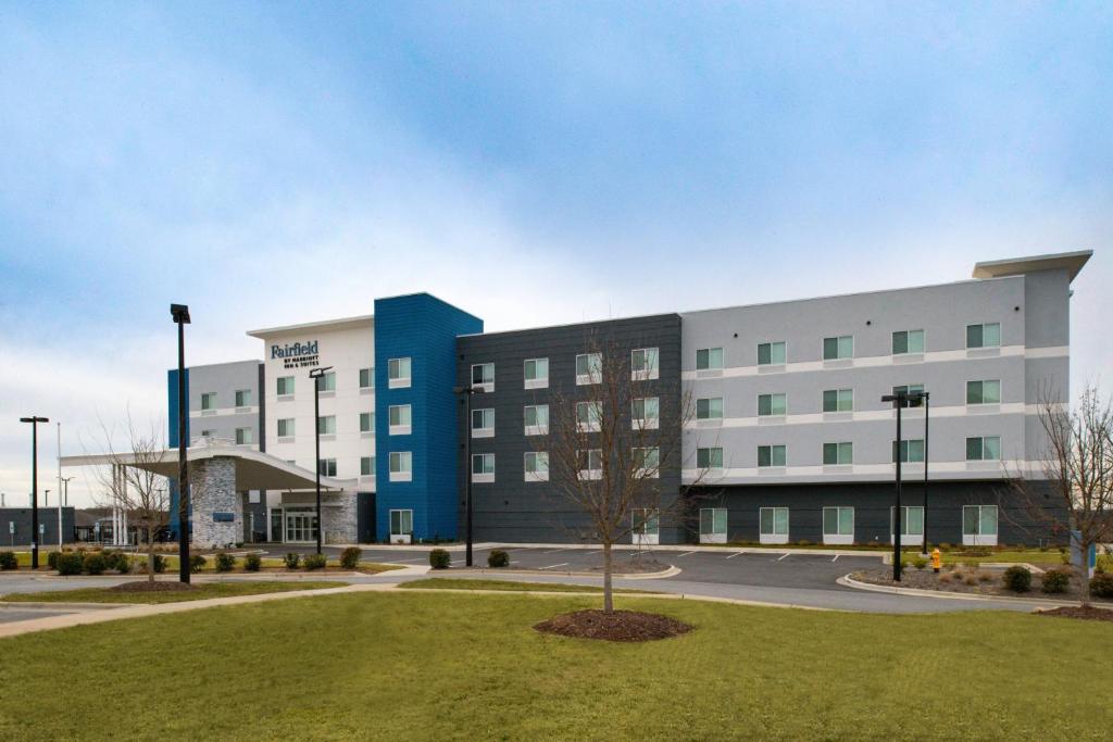 un grand bâtiment blanc avec un arbre en face dans l'établissement Fairfield Inn & Suites by Marriott Charlotte University Research Park, à Charlotte