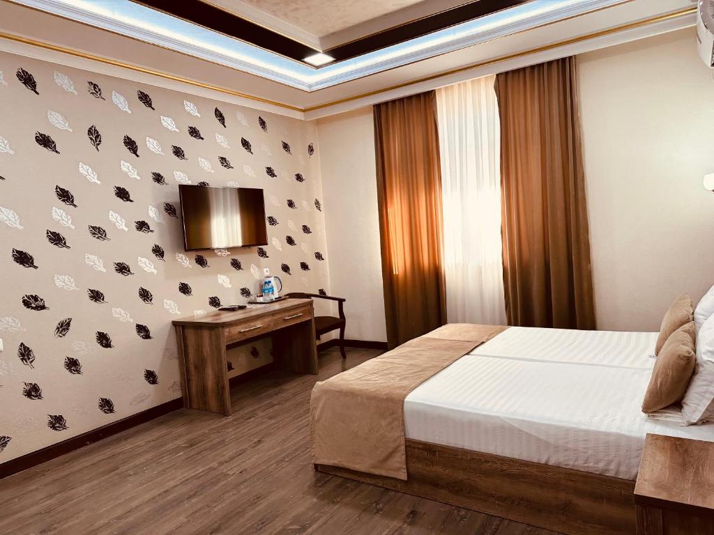 1 dormitorio con 1 cama, escritorio y TV en Grand Art Premium Hotel, en Tashkent