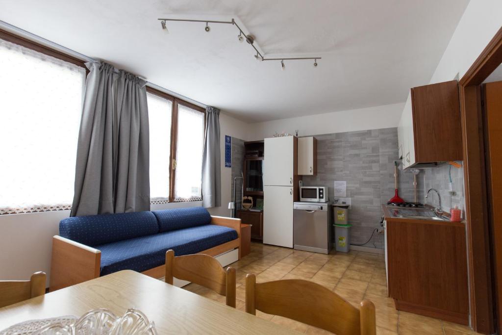 sala de estar con sofá azul y cocina en Casa Federica, en Molina di Ledro