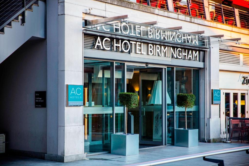 バーミンガムにあるAC Hotel by Marriott Birminghamの鉢植えの木が2本目の前にあるホテルの建物
