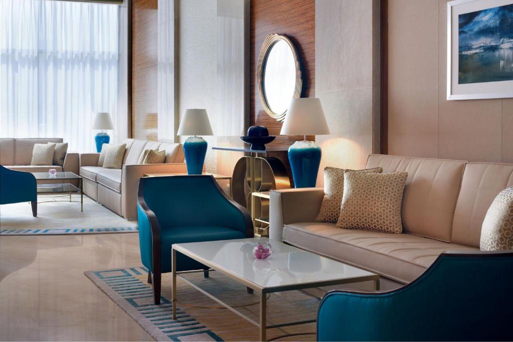 Marriott Executive Apartments Al Khobar في الخبر: غرفة معيشة مع أريكة وكراسي وطاولة