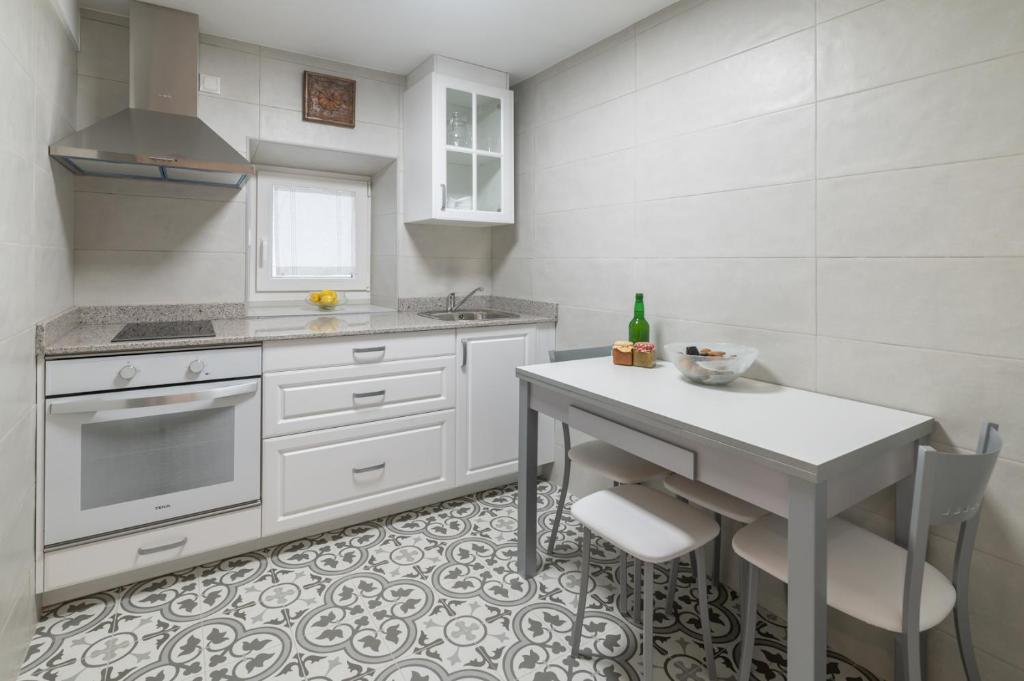 una cucina con armadi bianchi e tavolo con sedie di Pría, apartamento en Ribadesella a Ribadesella