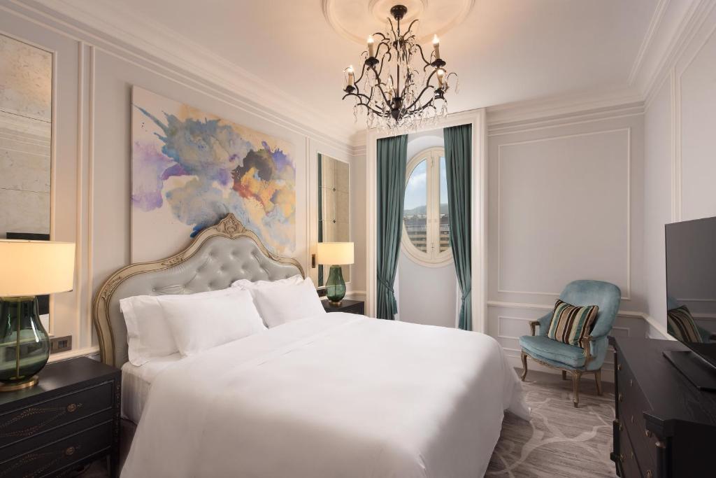 a bedroom with a white bed and a chandelier at Hotel Maria Cristina, a Luxury Collection Hotel, San Sebastian in Donostia-San Sebastián