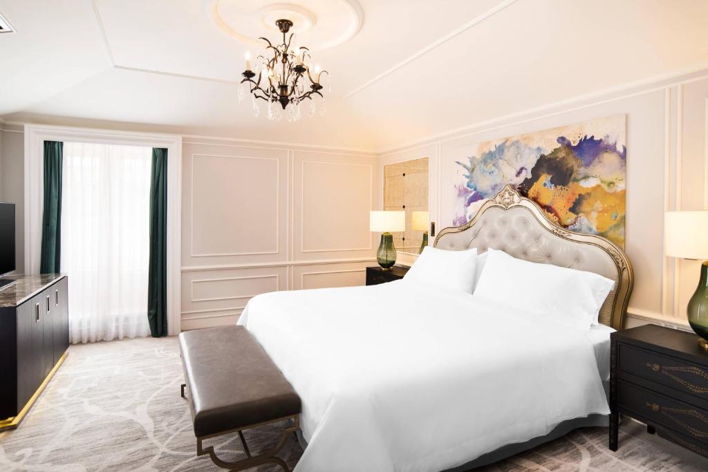 a bedroom with a large white bed and a chandelier at Hotel Maria Cristina, a Luxury Collection Hotel, San Sebastian in Donostia-San Sebastián