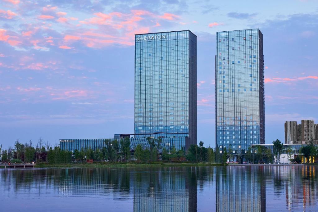 two tall skyscrapers in a city next to a lake at Sheraton Chengdu Pidu in Chengdu