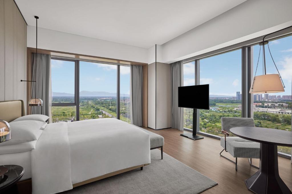 a bedroom with a white bed and a table and chairs at Sheraton Chengdu Pidu in Chengdu