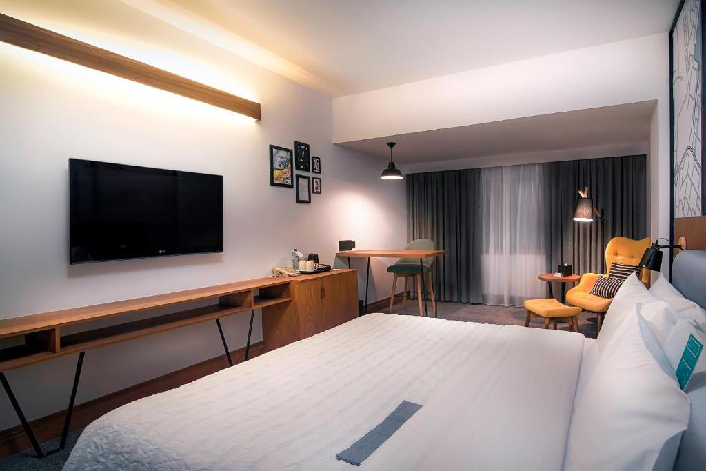 a hotel room with a bed and a desk with a television at Le Meridien Abu Dhabi in Abu Dhabi