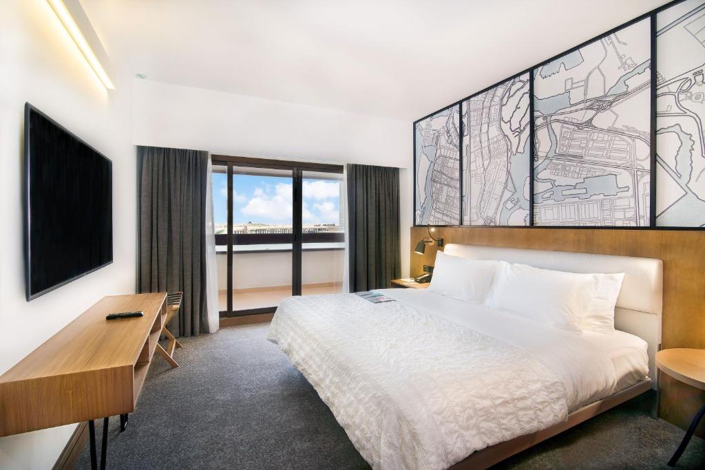 a hotel room with a bed and a desk and window at Le Meridien Abu Dhabi in Abu Dhabi