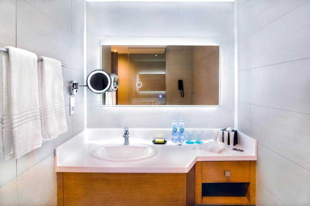 a white bathroom with a sink and a mirror at Le Meridien Abu Dhabi in Abu Dhabi