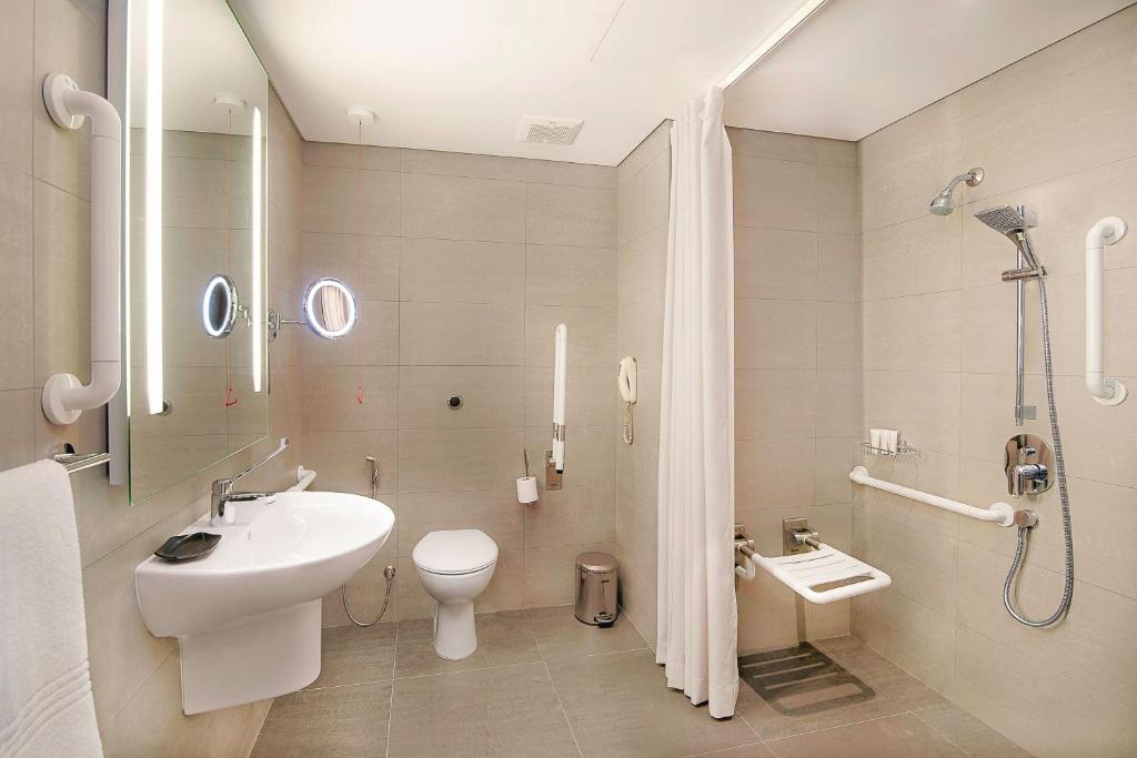 a bathroom with a sink and a toilet and a shower at Le Meridien Abu Dhabi in Abu Dhabi