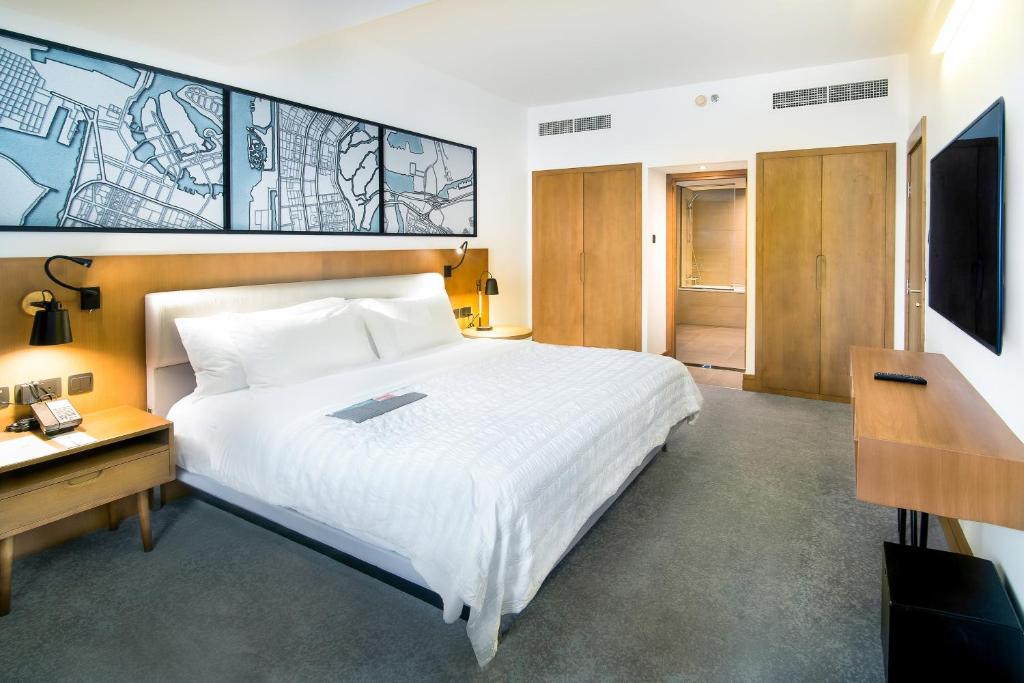 a bedroom with a bed and a desk and a television at Le Meridien Abu Dhabi in Abu Dhabi