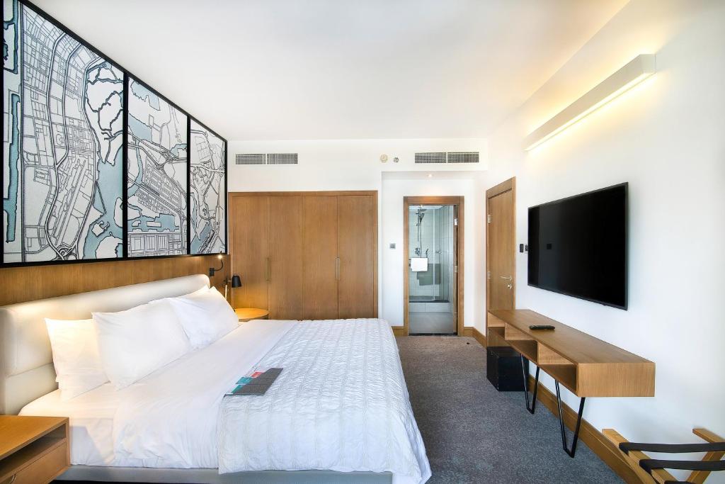 a bedroom with a bed and a desk and a tv at Le Meridien Abu Dhabi in Abu Dhabi