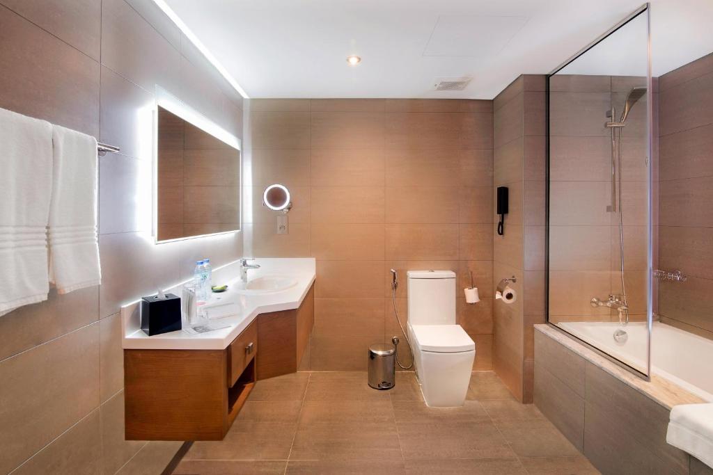 a bathroom with a toilet and a sink and a shower at Le Meridien Abu Dhabi in Abu Dhabi