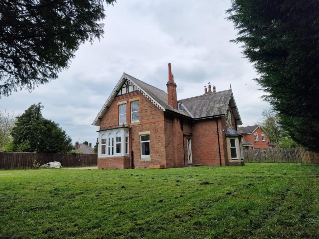 ein altes Backsteinhaus auf einem Grasfeld in der Unterkunft Dawson House in Darlington