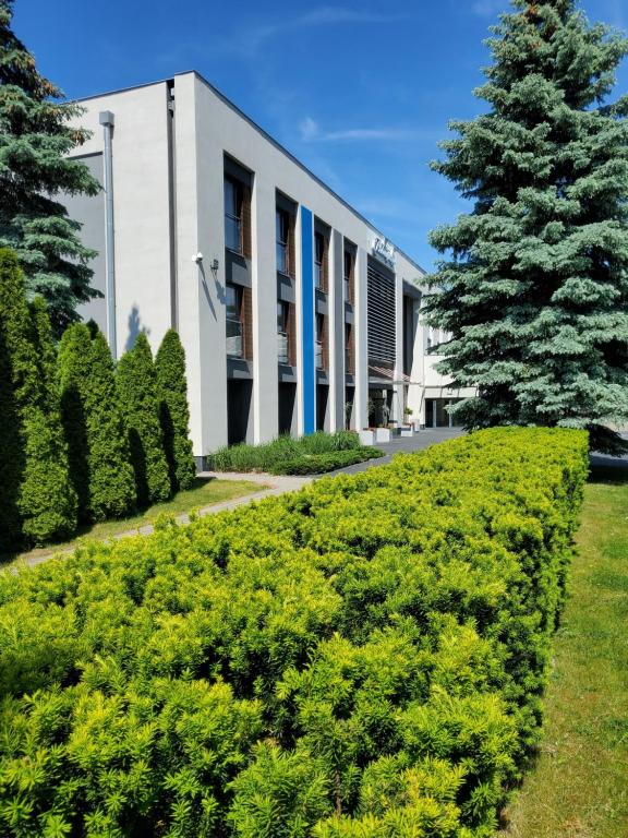 une haie devant un bâtiment avec un arbre dans l'établissement Antonińska Resort SPA, à Boszkowo