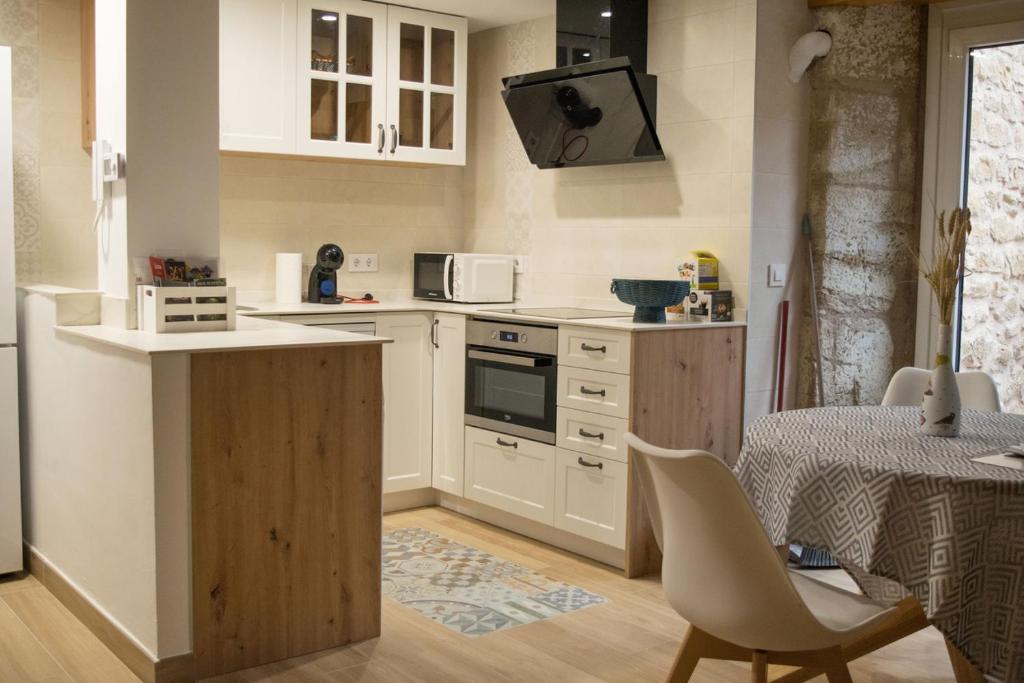 埃爾謝戈的住宿－En BLANCO y TINTO，厨房配有白色橱柜、桌子和椅子