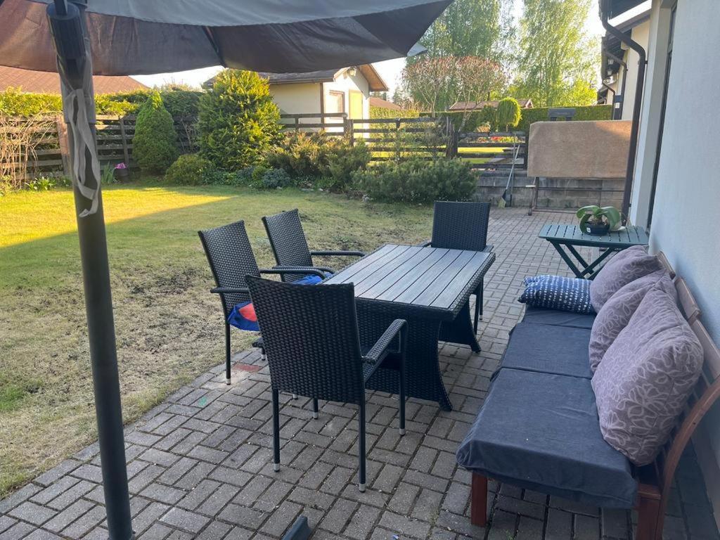 eine Terrasse mit einem Tisch, Stühlen und einem Sonnenschirm in der Unterkunft Casa del bosque in Upesciems