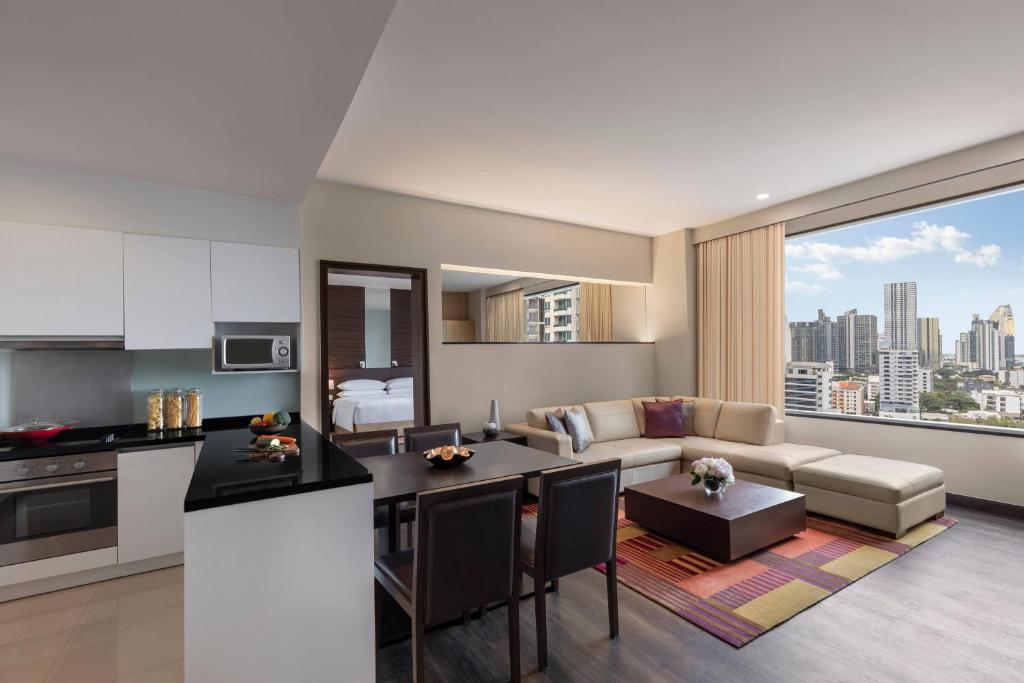 a kitchen and living room with a couch and a table at Marriott Executive Apartments - Sukhumvit Park, Bangkok in Bangkok