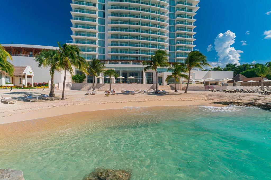 The Westin Cozumel في كوزوميل: شاطئ فيه نخيل ومبنى كبير