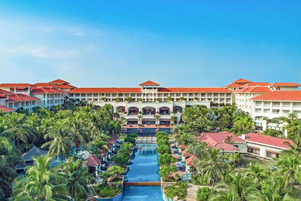 海口市にあるSheraton Haikou Hotelのプールとヤシの木があるリゾートの空中ビュー