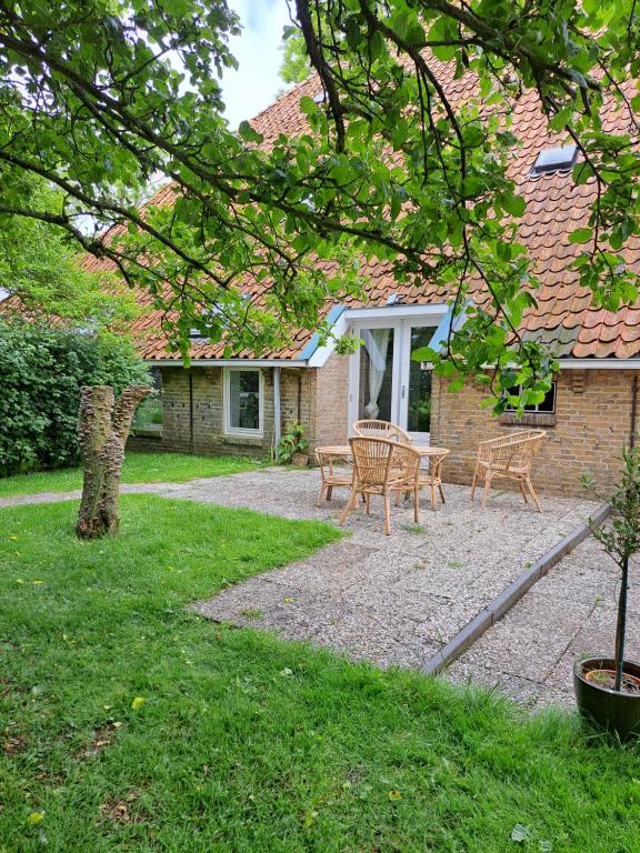 un patio con mesa y sillas frente a una casa en vakantiehuisje De achte, en Wommels