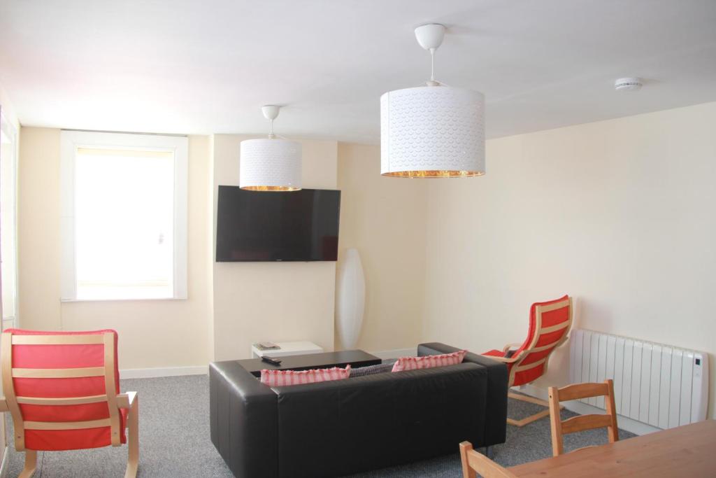 a living room with a black couch and chairs at Spacious Townhouse in Youghal