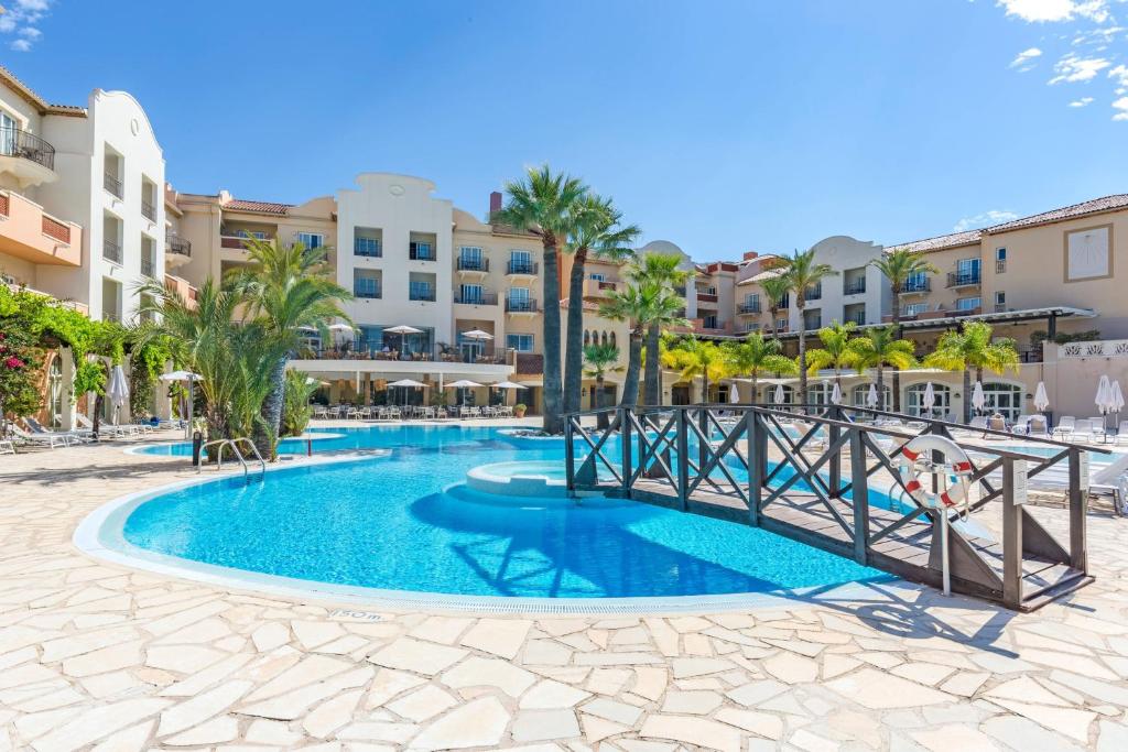 einen Pool im Resort mit Palmen und Gebäuden in der Unterkunft Denia Marriott La Sella Golf Resort & Spa in Denia