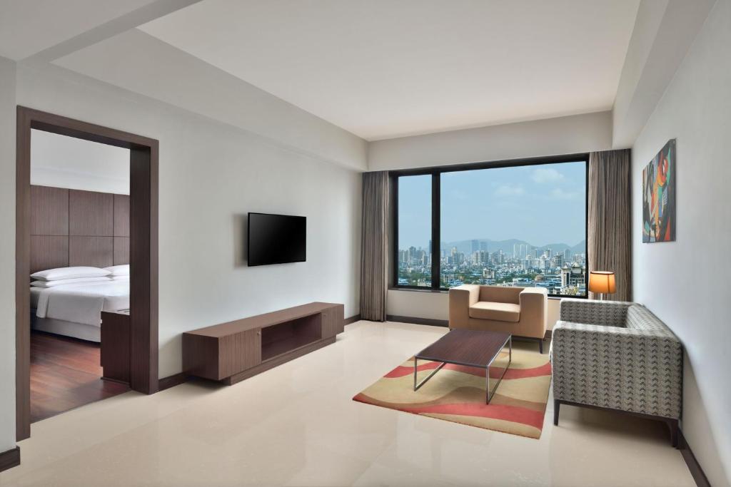 una camera d'albergo con letto e soggiorno di Four Points by Sheraton Navi Mumbai, Vashi a Navi Mumbai
