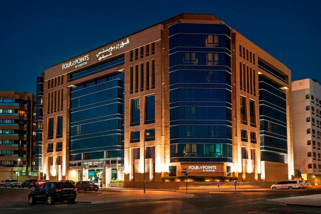 a large glass building in a city at night at Four Points by Sheraton Bur Dubai in Dubai