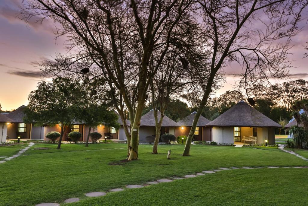 a resort with a tree and some buildings at Protea Hotel by Marriott Oudtshoorn Riempie Estate in Oudtshoorn