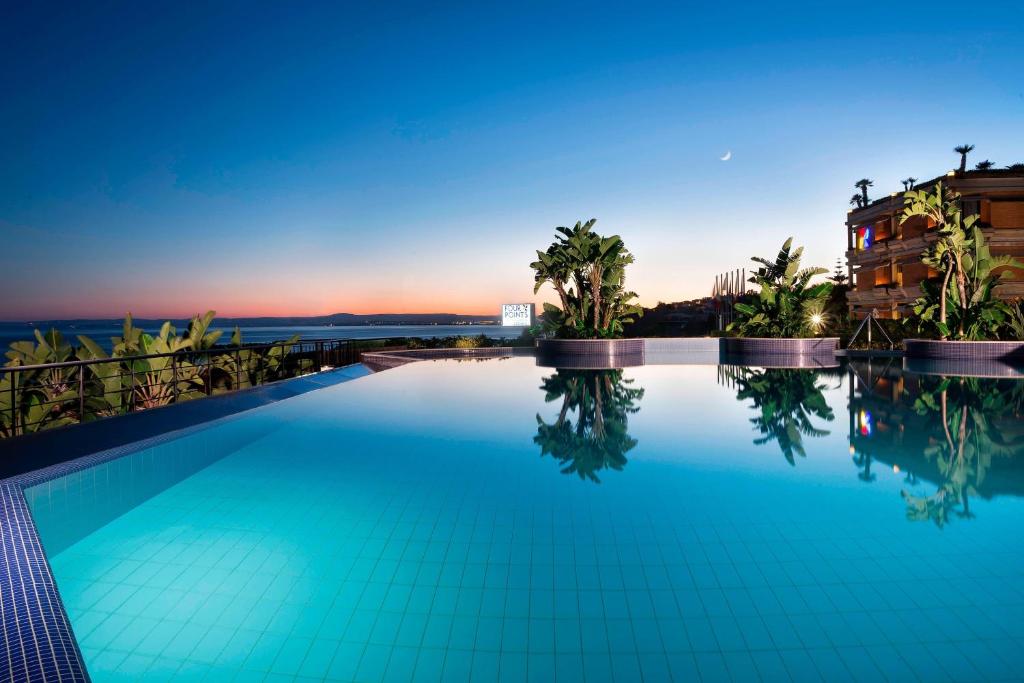 une piscine avec vue sur le coucher du soleil en arrière-plan dans l'établissement Four Points by Sheraton Catania Hotel, à Catane