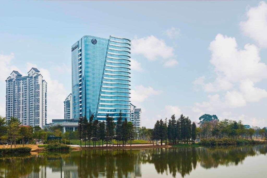 un grand bâtiment à côté d'une masse d'eau dans l'établissement Sheraton Guangzhou Nansha Hotel, à Canton