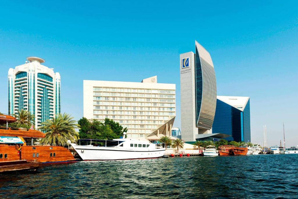 una barca bianca è ormeggiata di fronte a una città di Sheraton Dubai Creek Hotel & Towers a Dubai