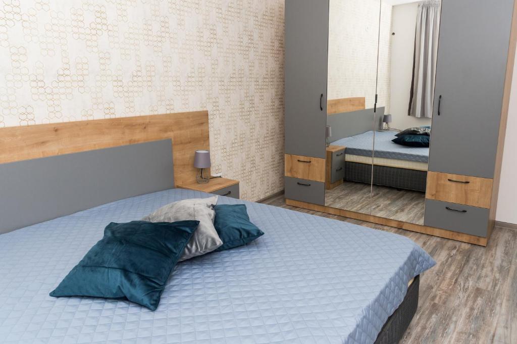 1 dormitorio con cama con almohadas azules y espejo en Alagen Apartments Burgas en Burgas