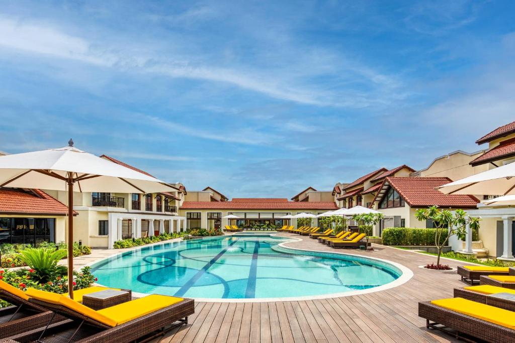 una piscina en un complejo con sillas y sombrillas en Fairfield by Marriott Goa Benaulim, en Benaulim