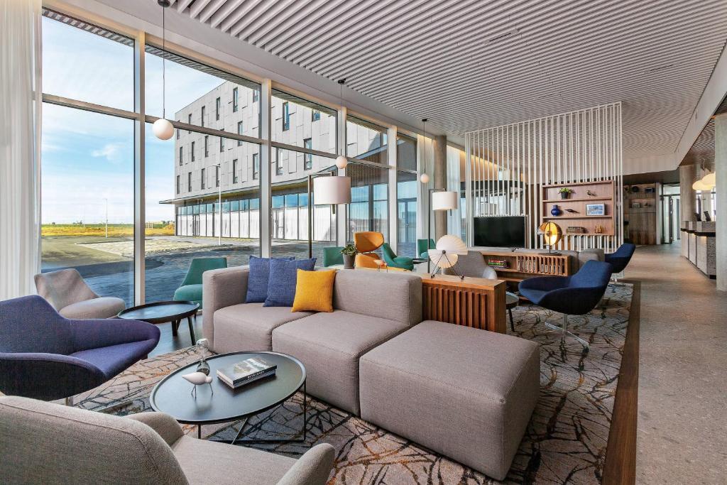 a living room with a couch and chairs and windows at Courtyard by Marriott Reykjavik Keflavik Airport in Keflavík