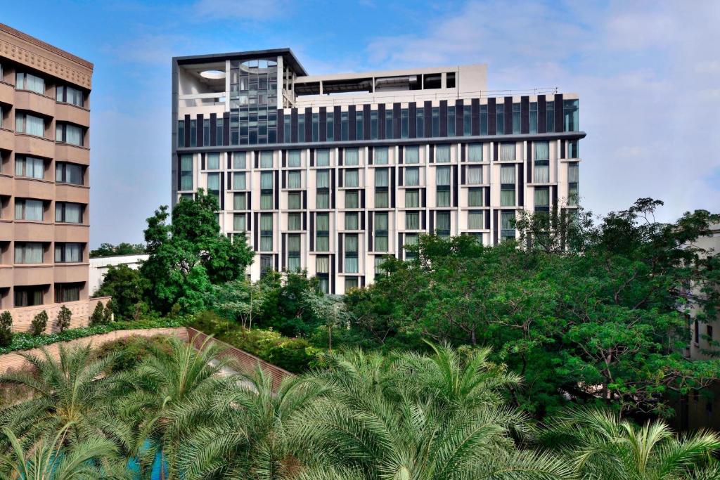 un edificio alto con árboles delante de él en Courtyard by Marriott Hyderabad, en Hyderabad