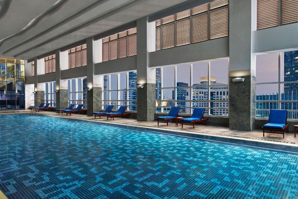una piscina en un hotel con sillas azules en The Mayflower, Jakarta-Marriott Executive Apartments en Yakarta