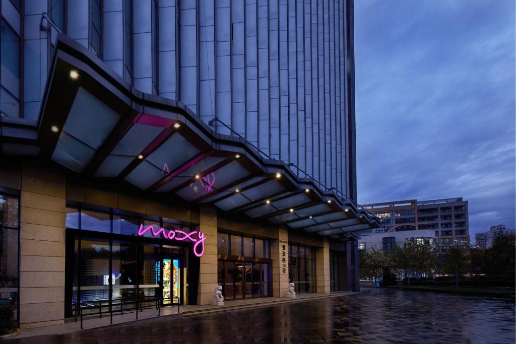 a building with a neon sign on the side of it at Moxy Shanghai Xuhui in Shanghai