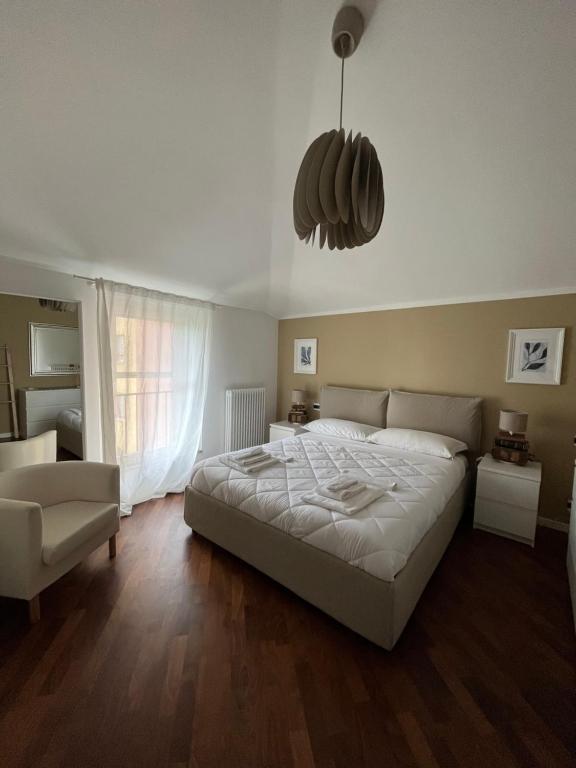 una camera con un grande letto bianco e una sedia di La Rocca Luxury Apartment a Parma