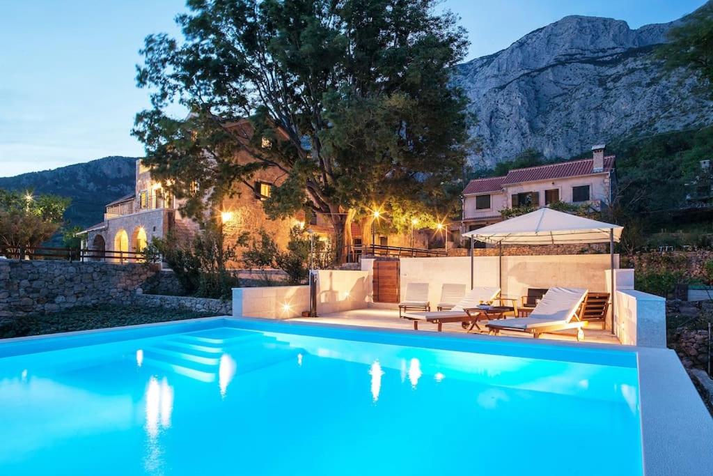 a swimming pool with two lounge chairs and a house at Charming stone villa Silva in Tučepi