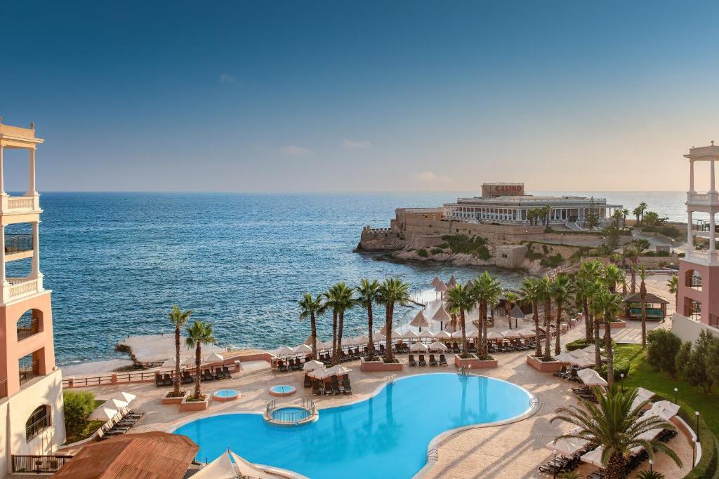 - une vue aérienne sur un complexe avec une piscine et l'océan dans l'établissement The Westin Dragonara Resort, Malta, à San Ġiljan